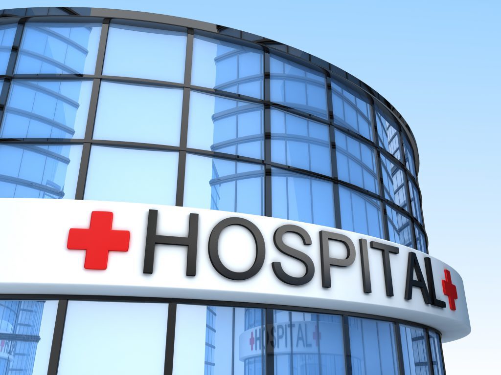 The front of a hospital with the sign which reads, "hospital."