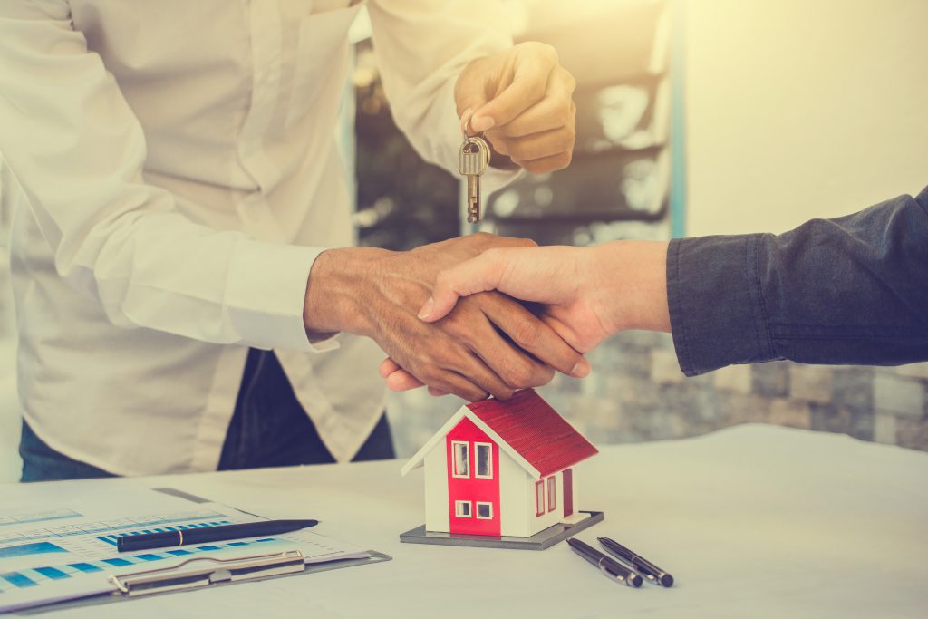 An agent handing the keys to a Milennial homebuyer.
